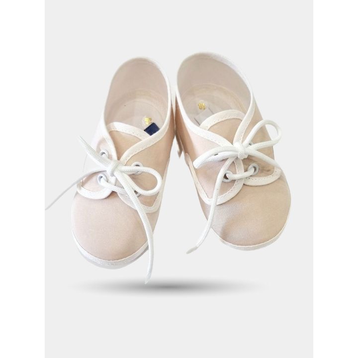 Coppia di scarpine beige vista di fronte con lacci bianchi annodati