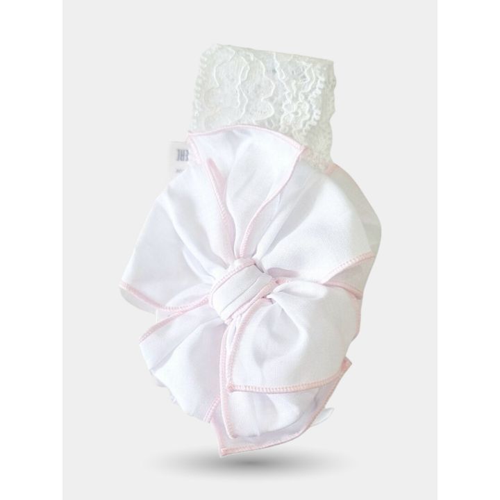 Fiore in tessuto bianco con bordi rosa visto da vicino sulla fascia