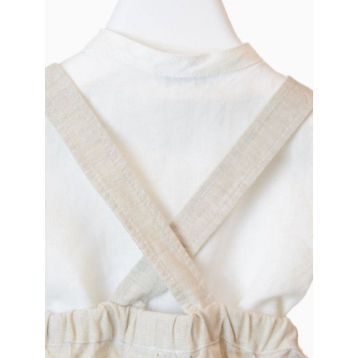 Dettaglio delle bretelle beige incrociate sul retro della camicia