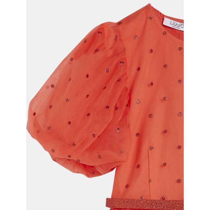 Dettaglio della manica a sbuffo in tulle rosso con pois glitter