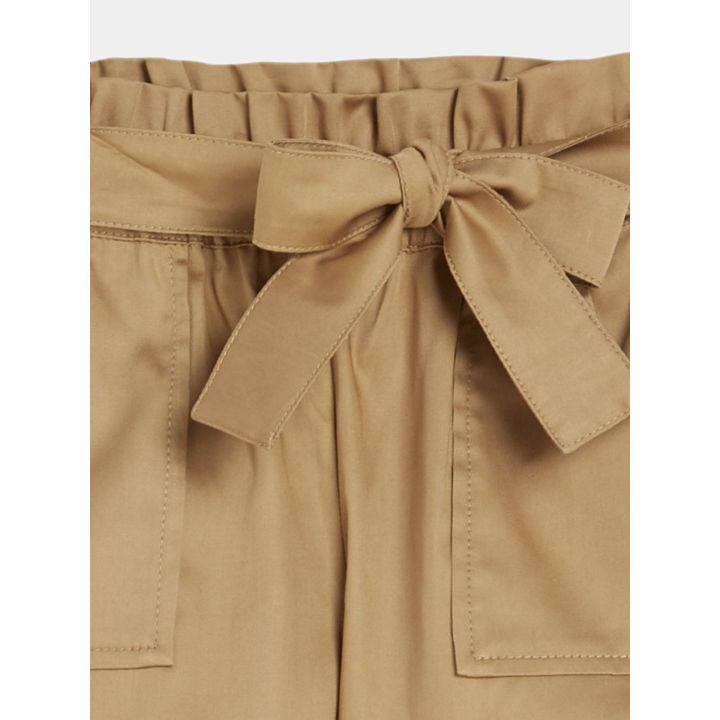Dettaglio del fiocco in tessuto sulla vita arricciata degli shorts marroni