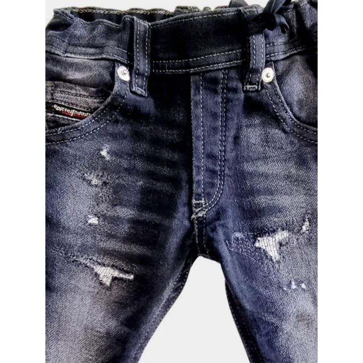 Dettaglio delle abrasioni e degli strappi sul davanti del jeans