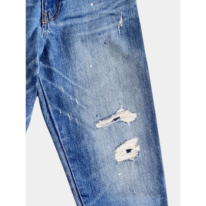 Dettaglio degli strappi e degli schizzi di colore sul jeans blu chiaro