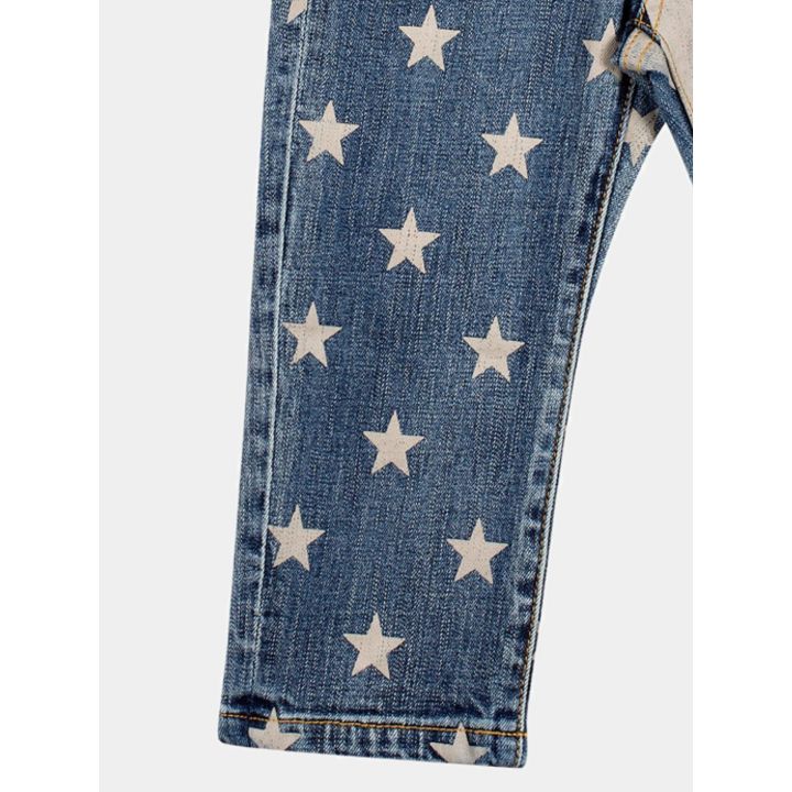 Dettaglio della gamba in denim blu con le stelle color panna