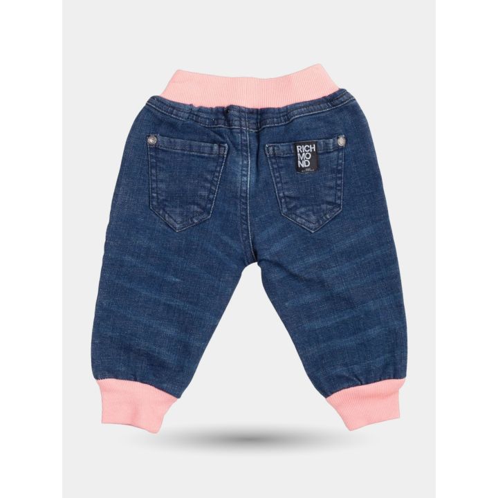 Retro del jeans blu con caviglie rosa ed etichetta nera sulla tasca