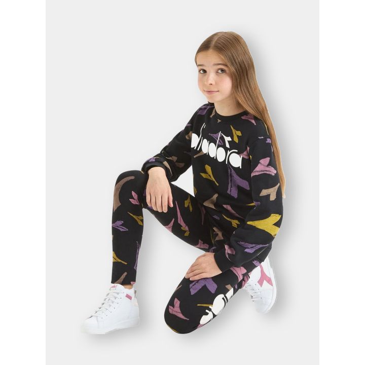 Bambina seduta con la felpa nera Diadora e i leggings nella stessa fantasia