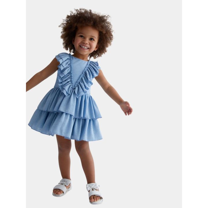 Bambina che balla con l'abito celeste a balze e sandali bianchi