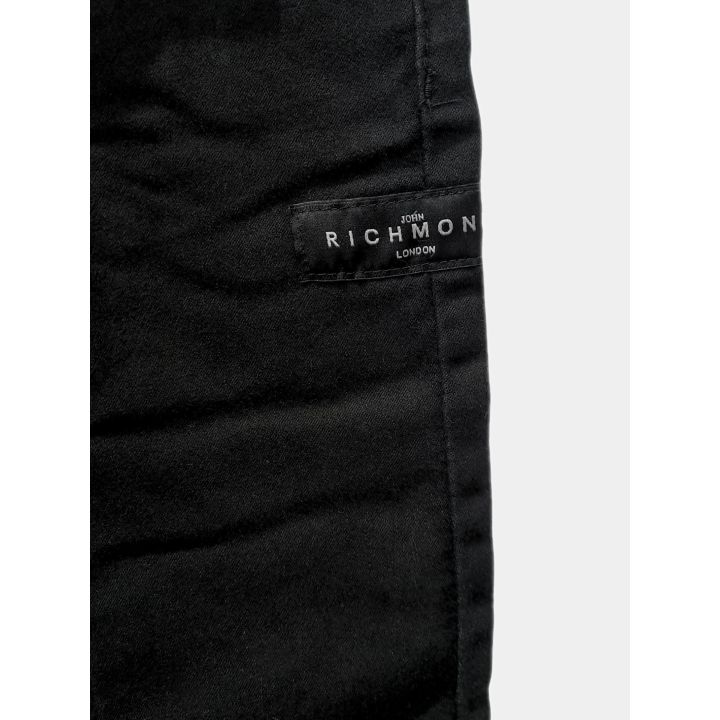 Dettaglio della patch Richmond London sulla gamba dei pantaloni neri