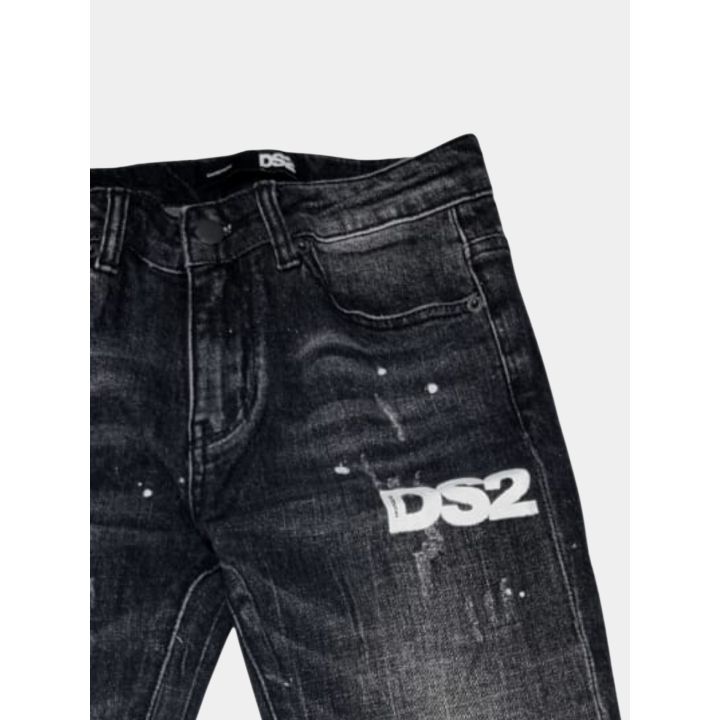 Dettaglio del logo DS2 bianco e degli schizzi di colore sui jeans neri