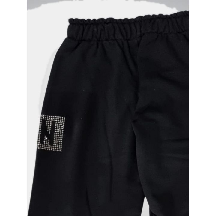 Dettaglio laterale del logo in strass sulla gamba del pantalone