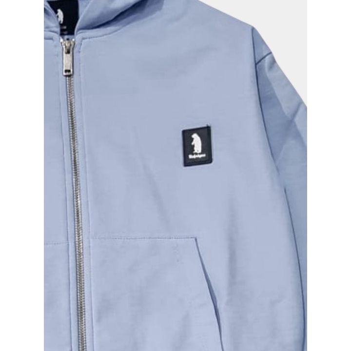 Dettaglio della felpa celeste con zip e patch gommata con l'orso