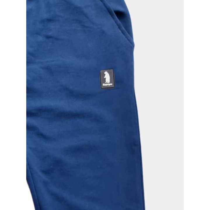 Dettaglio della patch con l'orso sulla gamba del pantalone blu