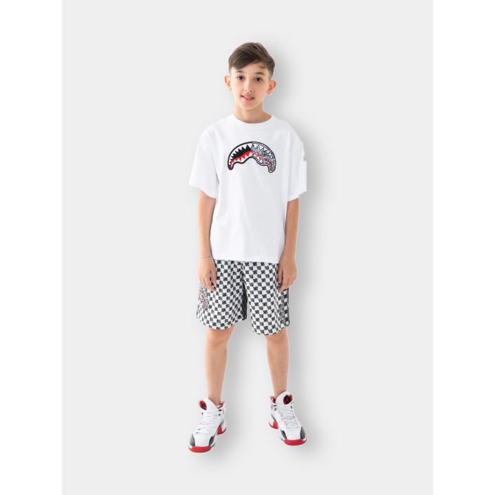 Bambino con la t-shirt Sprayground bianca e i pantaloncini a scacchi