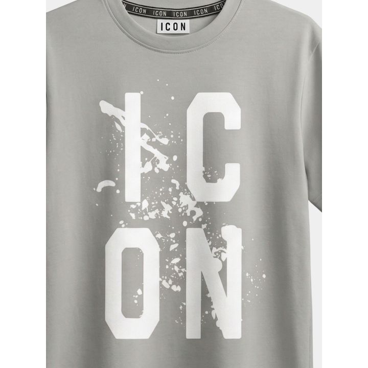 Dettaglio del logo ICON bianco con schizzi di vernice sulla t-shirt grigia