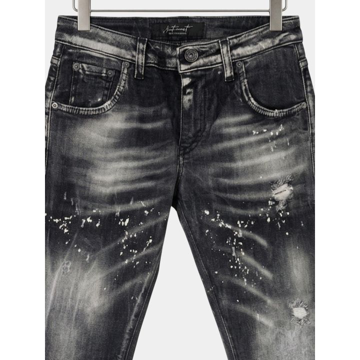 Dettaglio del davanti dei jeans grigi con schizzi bianchi e piccoli strappi