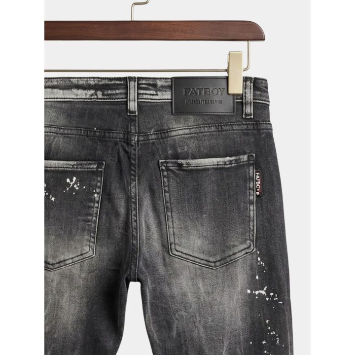 Dettaglio dell'etichetta nera e delle tasche posteriori dei jeans grigi