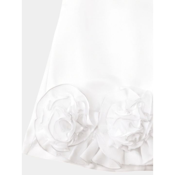 Dettaglio delle rose in tessuto sul fondo dell'abito bianco