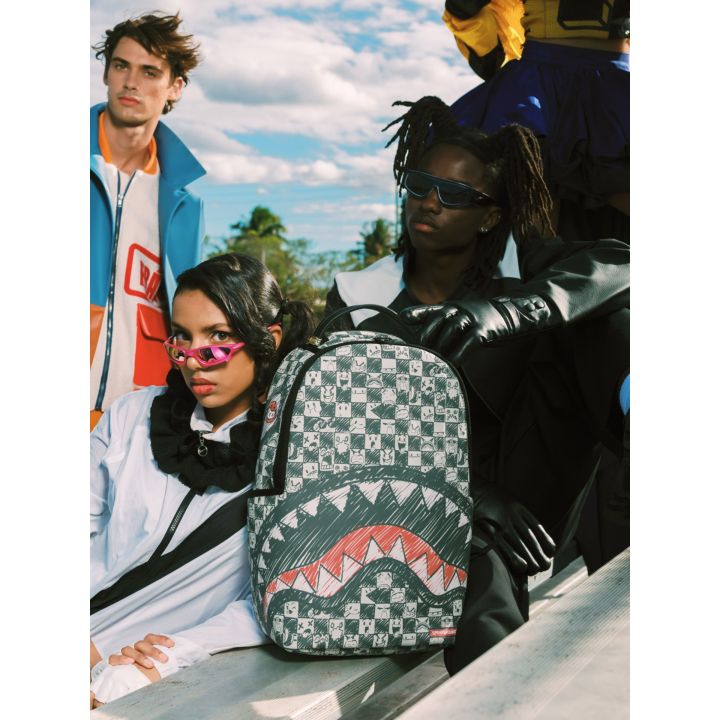 Tre ragazzi seduti all'aperto con lo zaino Sprayground Emote Check