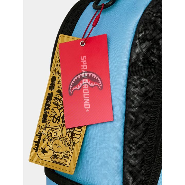 Dettaglio dei cartellini rosso e oro Sprayground sullo zaino blu