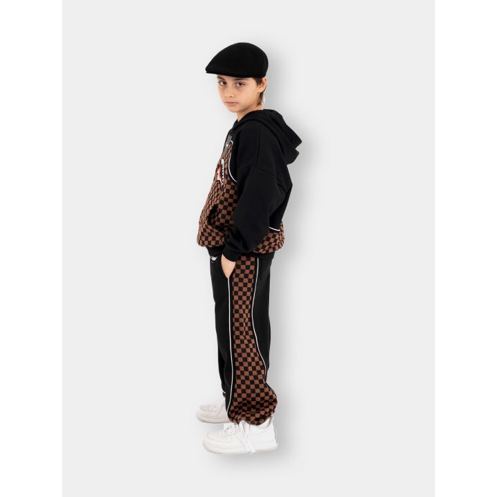 Ragazzo con la tuta Sprayground nera e marrone, vista laterale